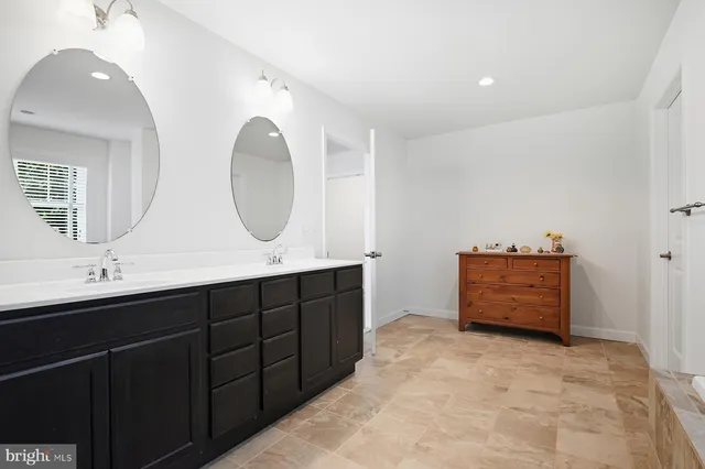 a spacious bathroom with a granite countertop tub a sink and a large mirror