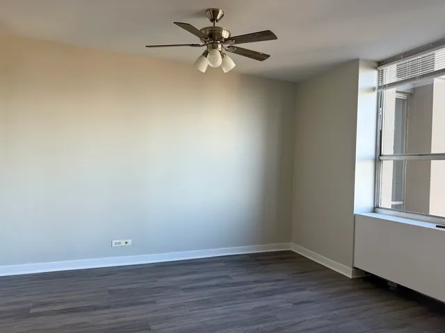 a view of an empty room with window and wooden floor