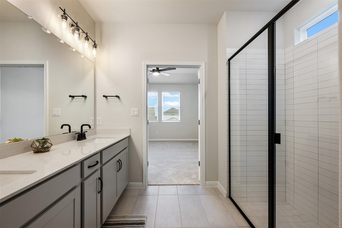 283 Ranier Way Dripping Springs, TX 78620 - Photo 24 of 39 Bathroom with healthy amount of natural light, double vanity, a stall shower, and a ceiling fan