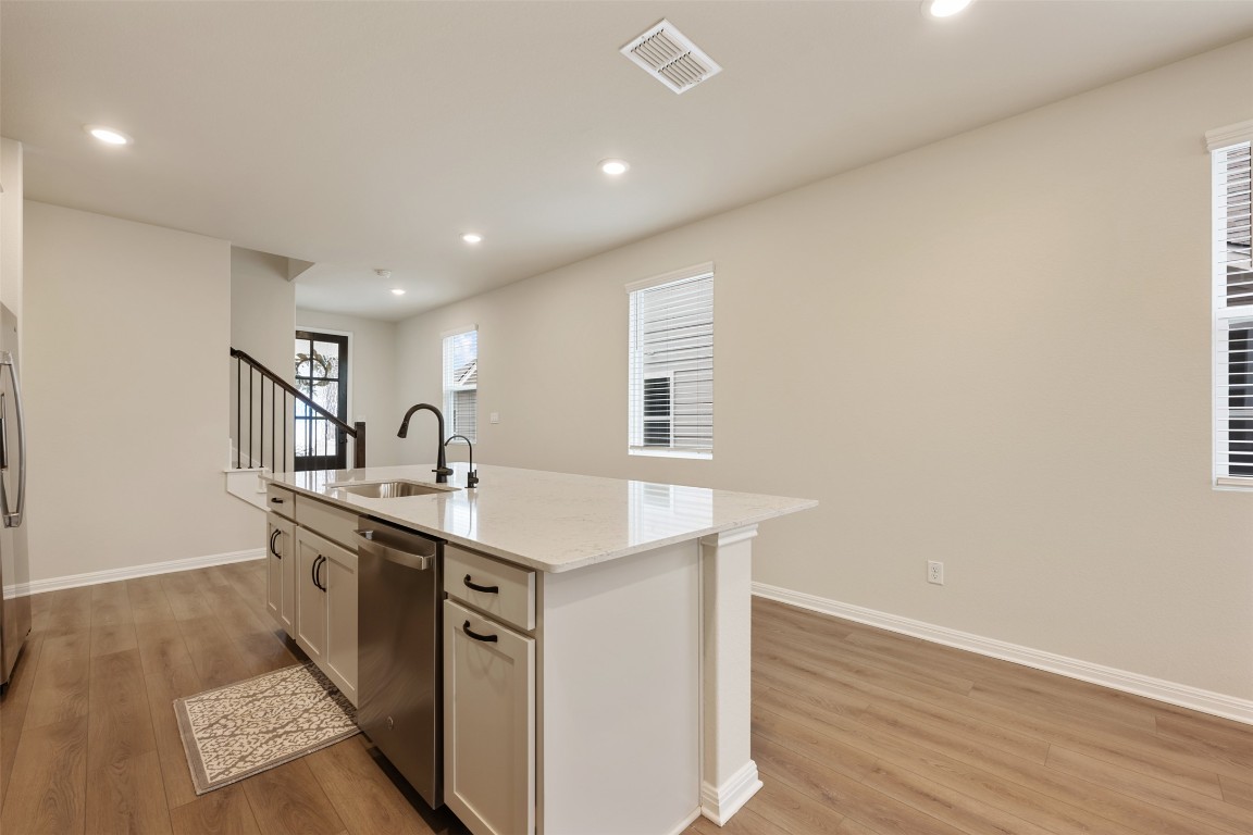 283 Ranier Way Dripping Springs, TX 78620 - Photo 8 of 39 Kitchen featuring light stone countertops, appliances with stainless steel finishes, light wood finished floors, recessed lighting, and a center island with sink
