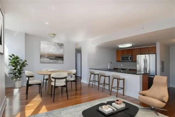 a living room with furniture kitchen view and a wooden floor