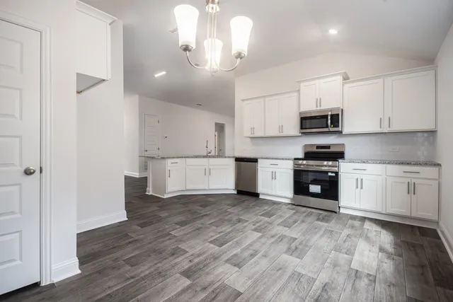 a kitchen with stainless steel appliances a white cabinets and wooden floor