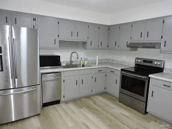 a kitchen with cabinets stainless steel appliances and wooden floor