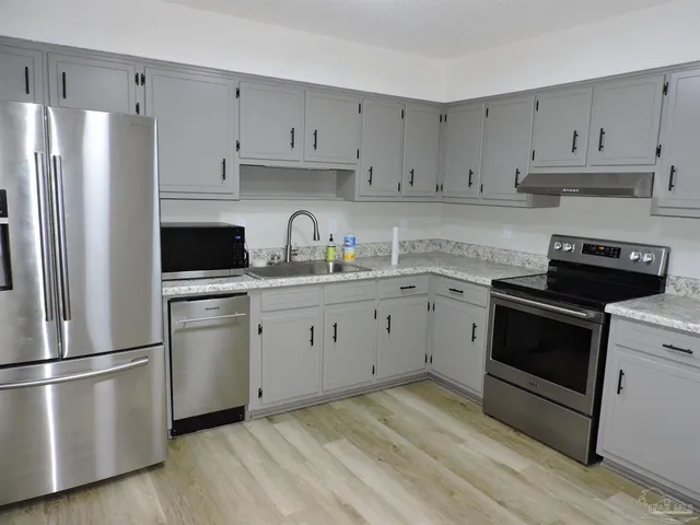 a kitchen with cabinets stainless steel appliances and wooden floor