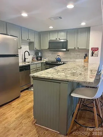 a kitchen with kitchen island granite countertop a sink counter top space appliances and cabinets