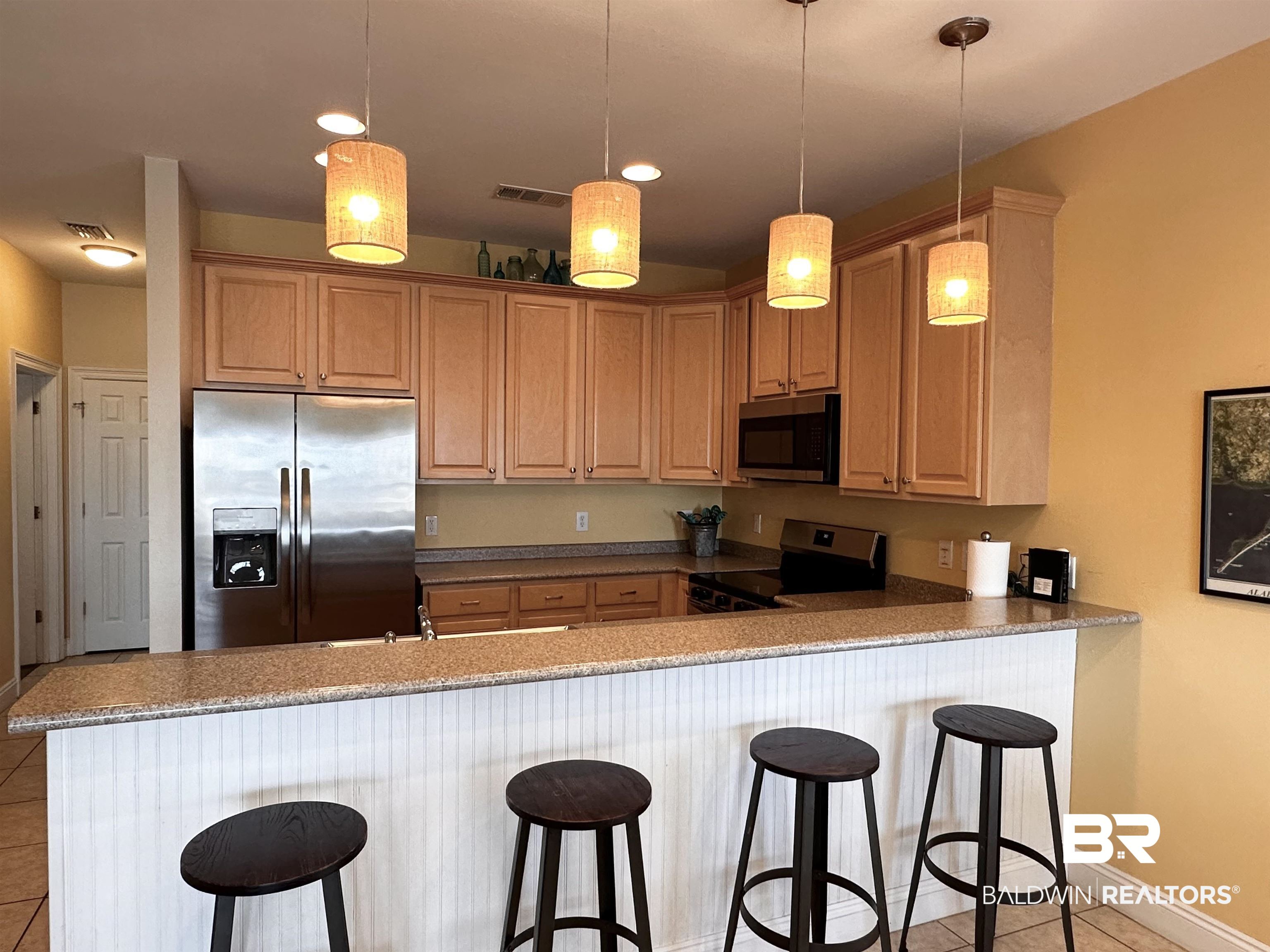 1472 Sandy Lane, Unit A Gulf Shores, AL 36542 - Photo 27 of 44 Kitchen featuring a breakfast bar, appliances with stainless steel finishes, kitchen peninsula, stone counters, and pendant lighting