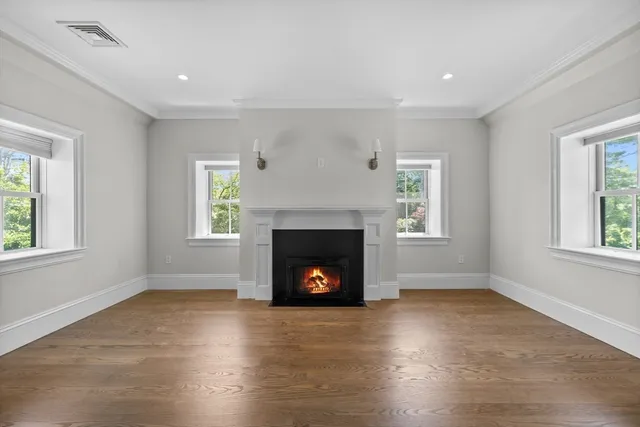 a view of a livingroom with a fireplace wooden floor and windows