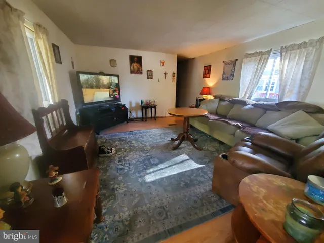 a living room with furniture and a flat screen tv with kitchen view