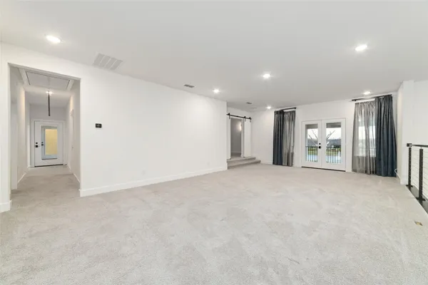 a view of an empty room with kitchen and a window