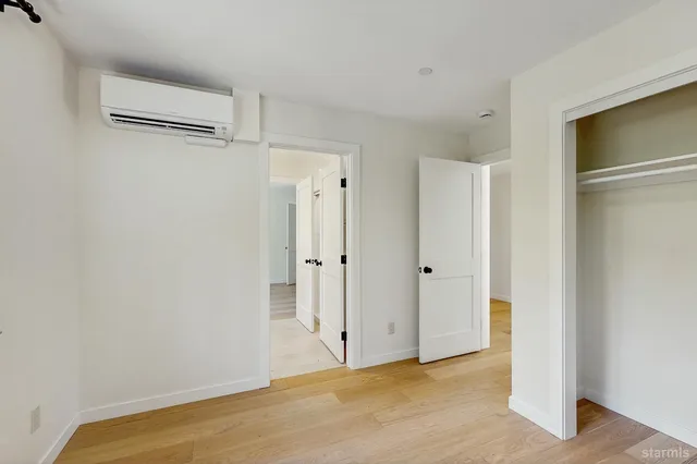 a view of an empty room with a window and wooden floor