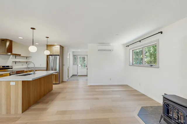 a large kitchen with stainless steel appliances kitchen island granite countertop a refrigerator a stove a sink dishwasher and white cabinets with wooden floor