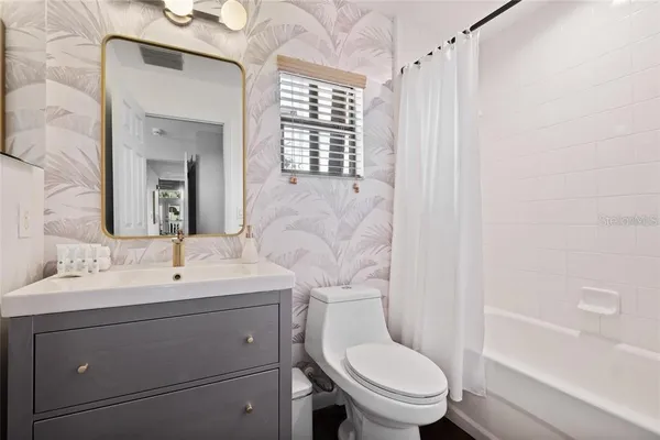 a bathroom with a toilet a sink a mirror a window and vanity