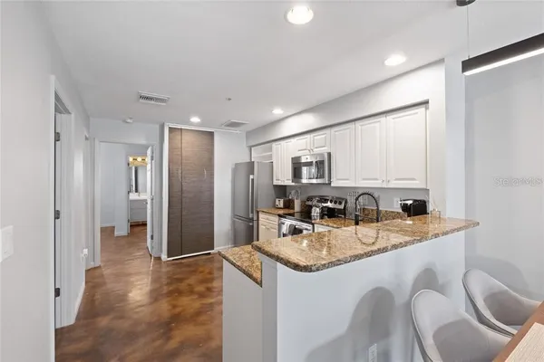 a kitchen with stainless steel appliances granite countertop a sink refrigerator and cabinets