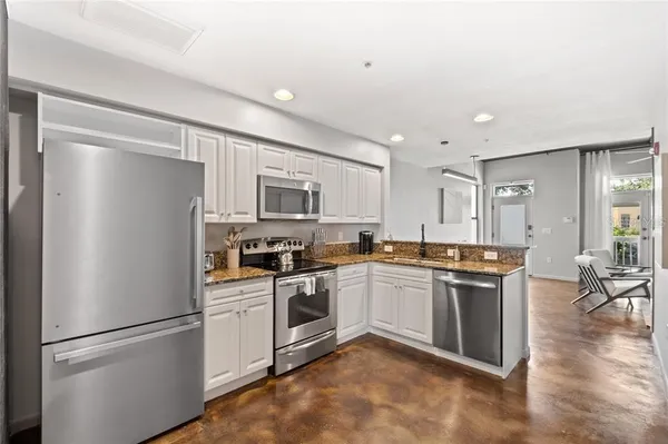 a kitchen with stainless steel appliances granite countertop a refrigerator a stove a sink and white cabinets