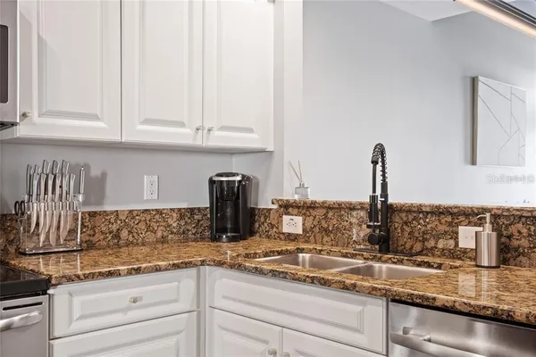a kitchen with granite countertop white cabinets and a sink