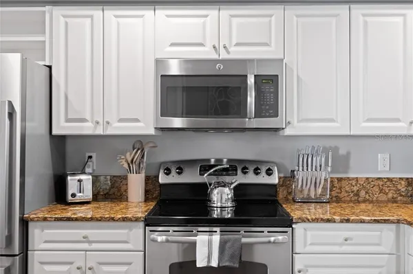 a kitchen with granite countertop white cabinets and black appliances