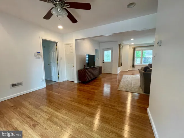 a view of a livingroom with furniture a ceiling fan and wooden floor
