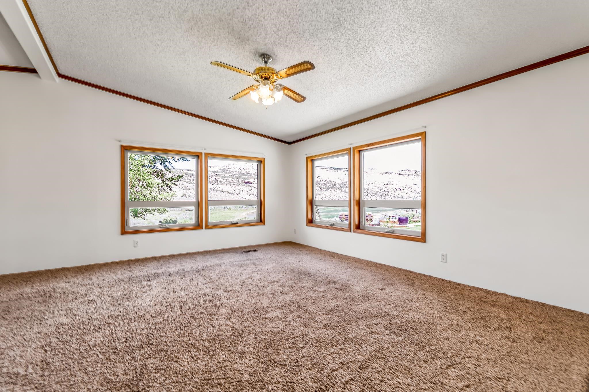 24591 Highway 64 Rangely, CO 81648 - Photo 17 of 42 an empty room with windows and chandelier fan