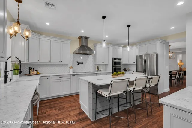 a kitchen with stainless steel appliances a stove a sink a refrigerator a center island a table and chairs