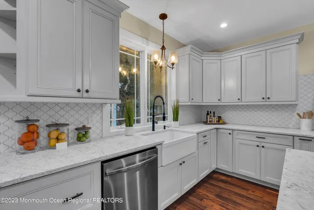 a kitchen with a sink dishwasher and white cabinets with wooden floor
