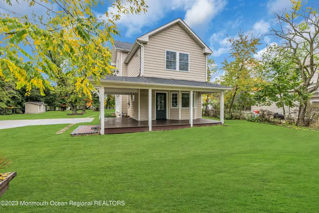 a view of a house next to a big yard and large trees
