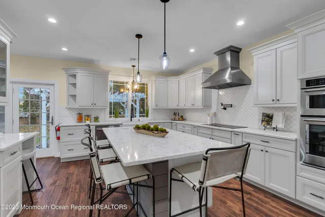 a kitchen with stainless steel appliances granite countertop a stove a refrigerator a kitchen island a table and chairs with wooden floor