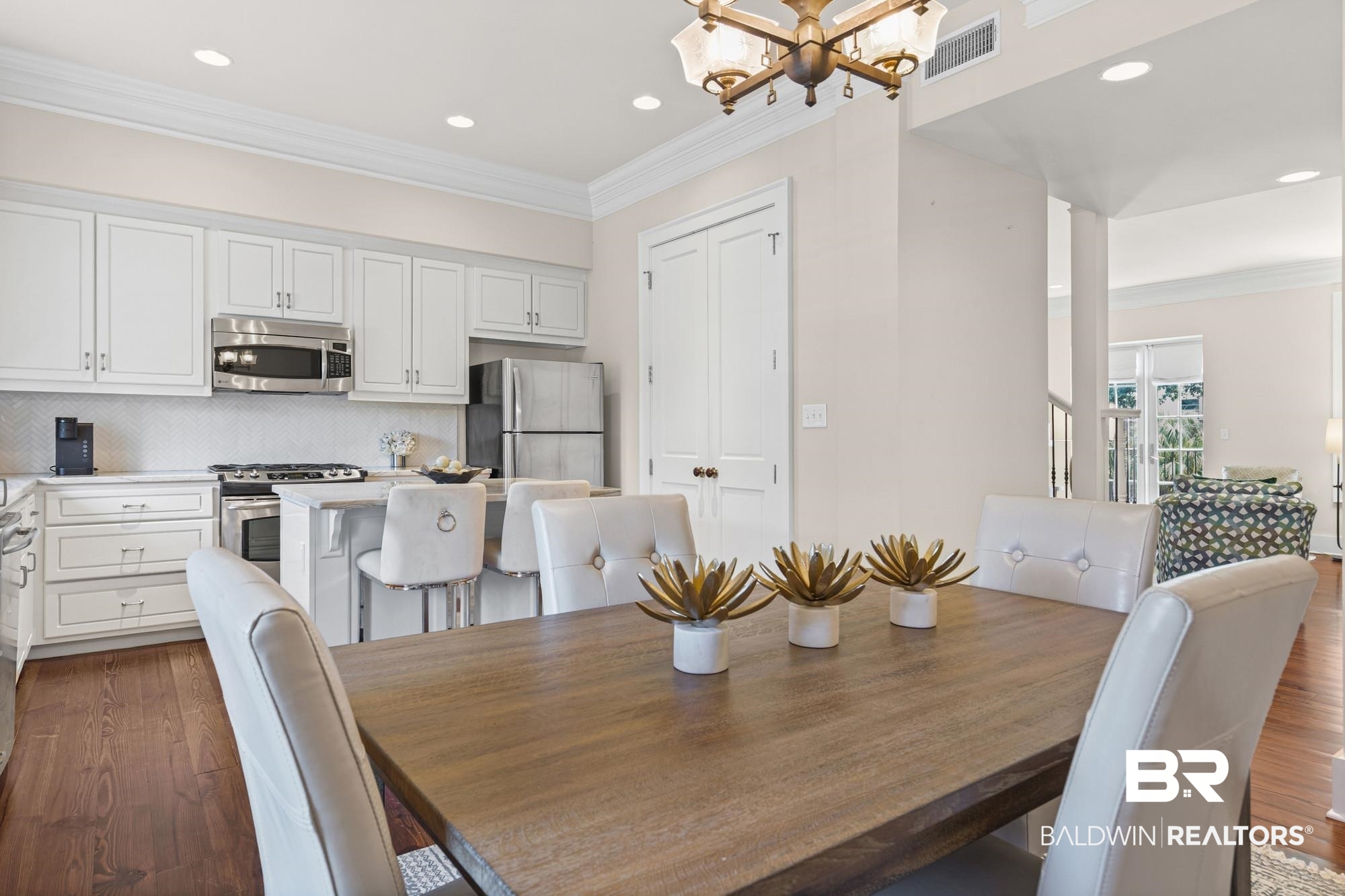 701 Dauphin Street, Unit A Mobile, AL 36602 - Photo 12 of 31 Kitchen and dining area featuring white cabinetry, stainless steel appliances, herringbone tile backsplash, and a dining bar with counter seating