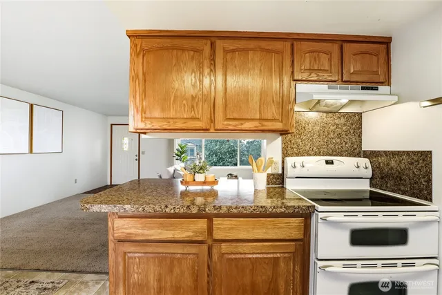 a kitchen with kitchen island granite countertop a stove a sink and a granite counter tops