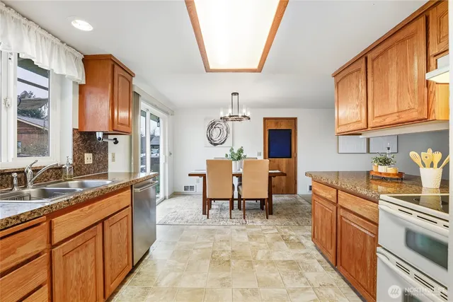 a large kitchen with stainless steel appliances granite countertop a sink and a refrigerator