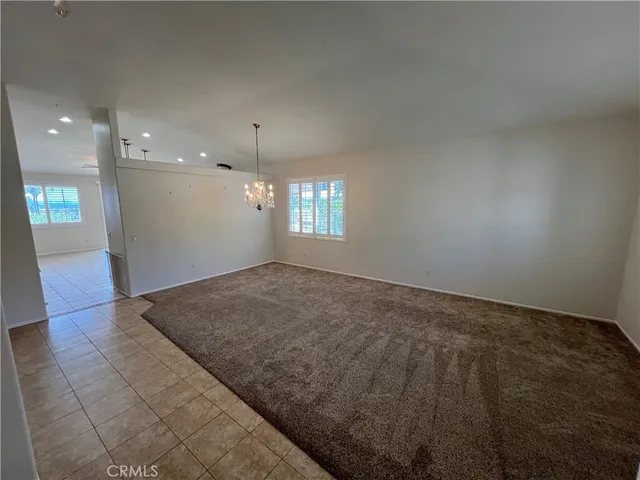 an empty room with kitchen view and natural light