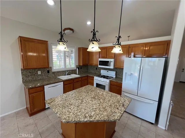 a kitchen with stainless steel appliances granite countertop sink stove and refrigerator