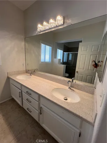 a bathroom with double vanity sink a vanity and a large mirror