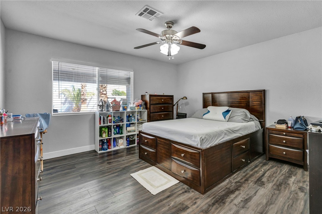 5882 Rio Tinto Way Las Vegas, NV 89110 - Photo 9 of 56 Wood-look flooring and a window with horizontal blinds complement this primary bedroom.