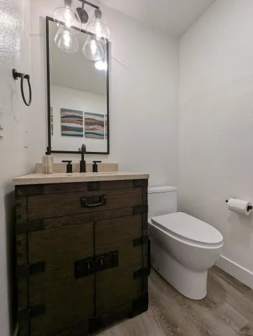 a bathroom with a toilet sink vanity and mirror