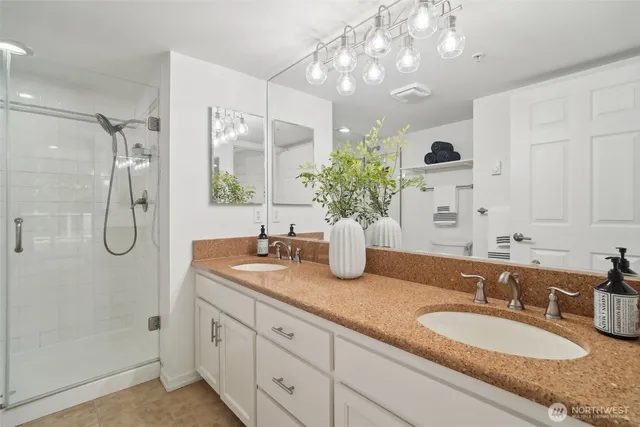 a bathroom with double vanity sinks a vanity a mirror and shower