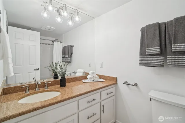 a bathroom with a granite countertop double vanity sink and mirror