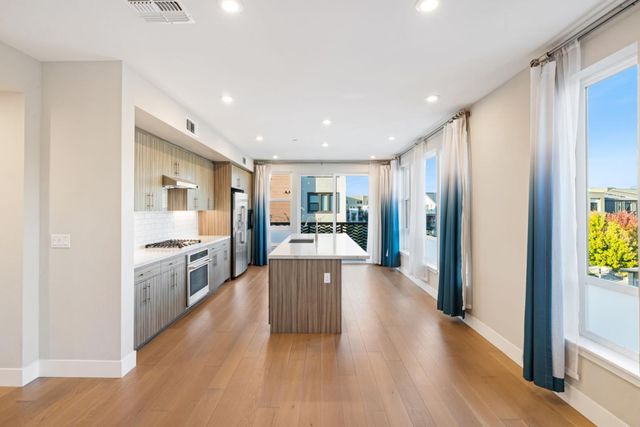a large kitchen with a lot of counter space a sink and stainless steel appliances