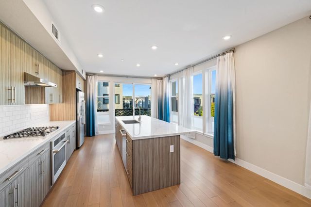 a large kitchen with stainless steel appliances granite countertop a large center island and a stove top oven