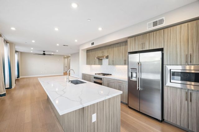 a kitchen with stainless steel appliances kitchen island granite countertop a refrigerator and a stove top oven