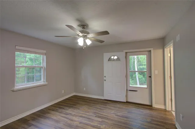 a view of an empty room with a window and wooden floor