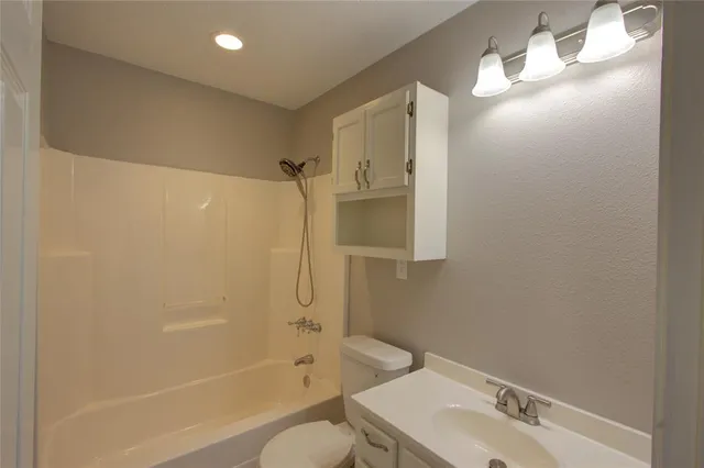 a bathroom with a bathtub shower sink vanity and toilet