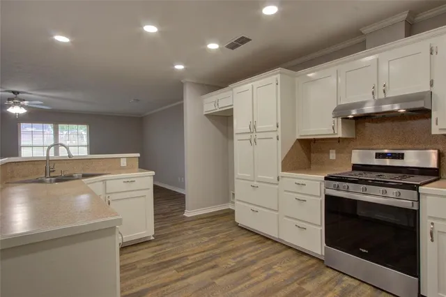 a kitchen with stainless steel appliances white cabinets and wooden floors