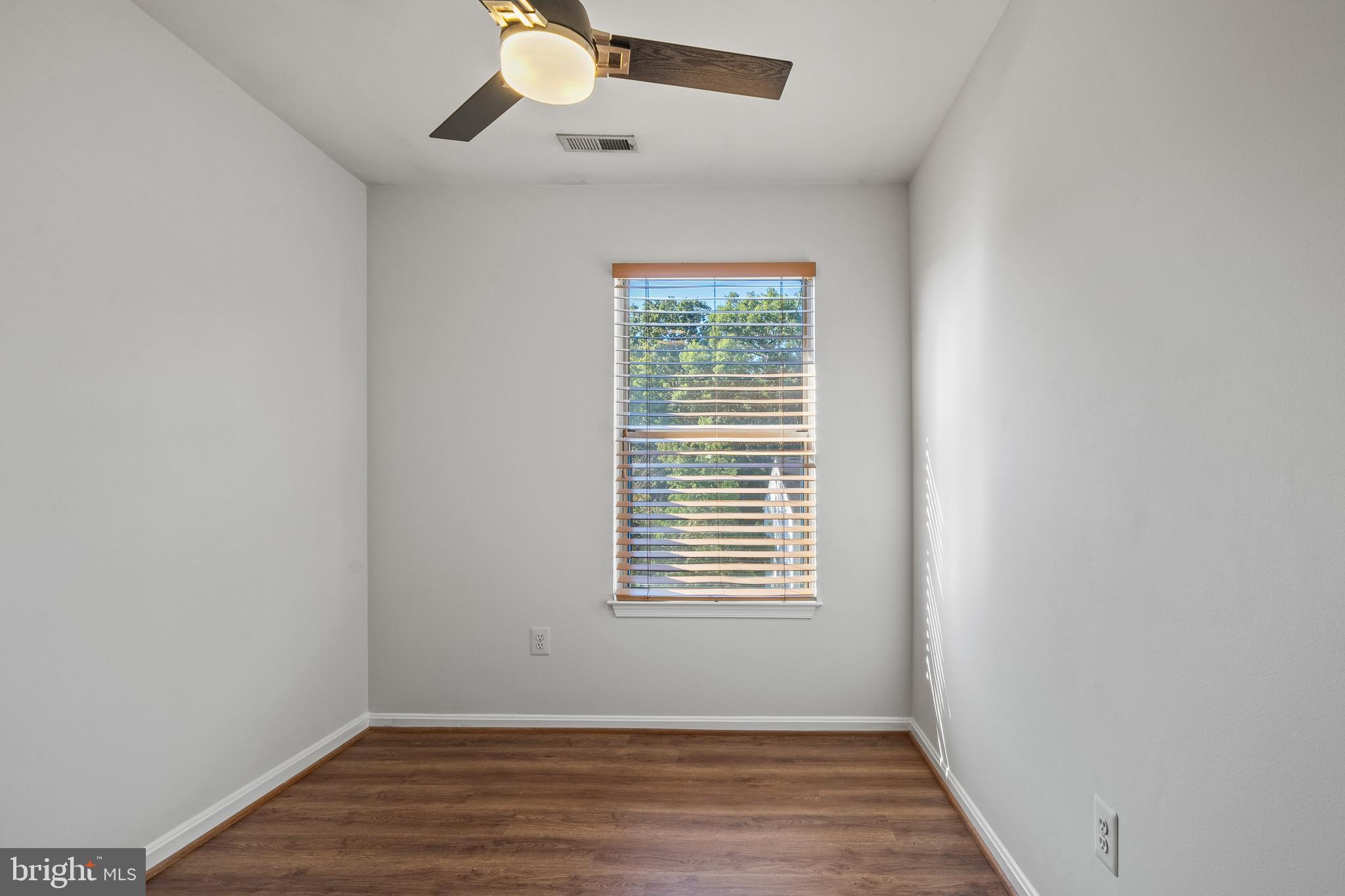 1132 Ingate Road, Unit 1132 Baltimore, MD 21227 - Photo 16 of 35 an empty room with wooden floor chandelier fan and windows