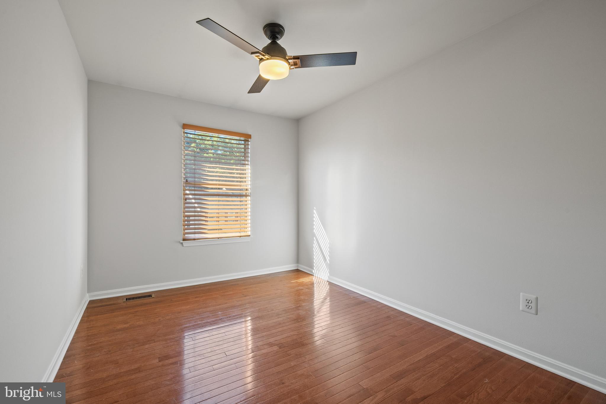 1132 Ingate Road, Unit 1132 Baltimore, MD 21227 - Photo 18 of 35 an empty room with wooden floor ceiling fan and windows