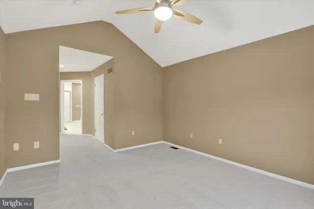 a view of an empty room with a chandelier fan