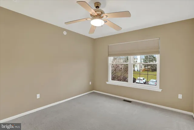 an empty room with a window and a ceiling fan