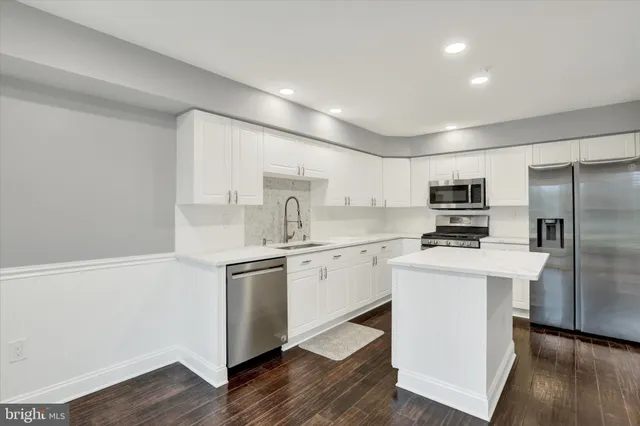 a kitchen with stainless steel appliances a sink cabinets and wooden floor