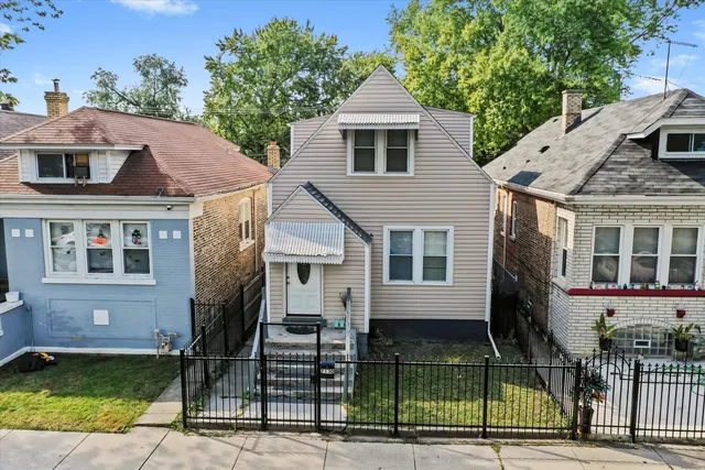 a view of a house with a small yard and a large tree