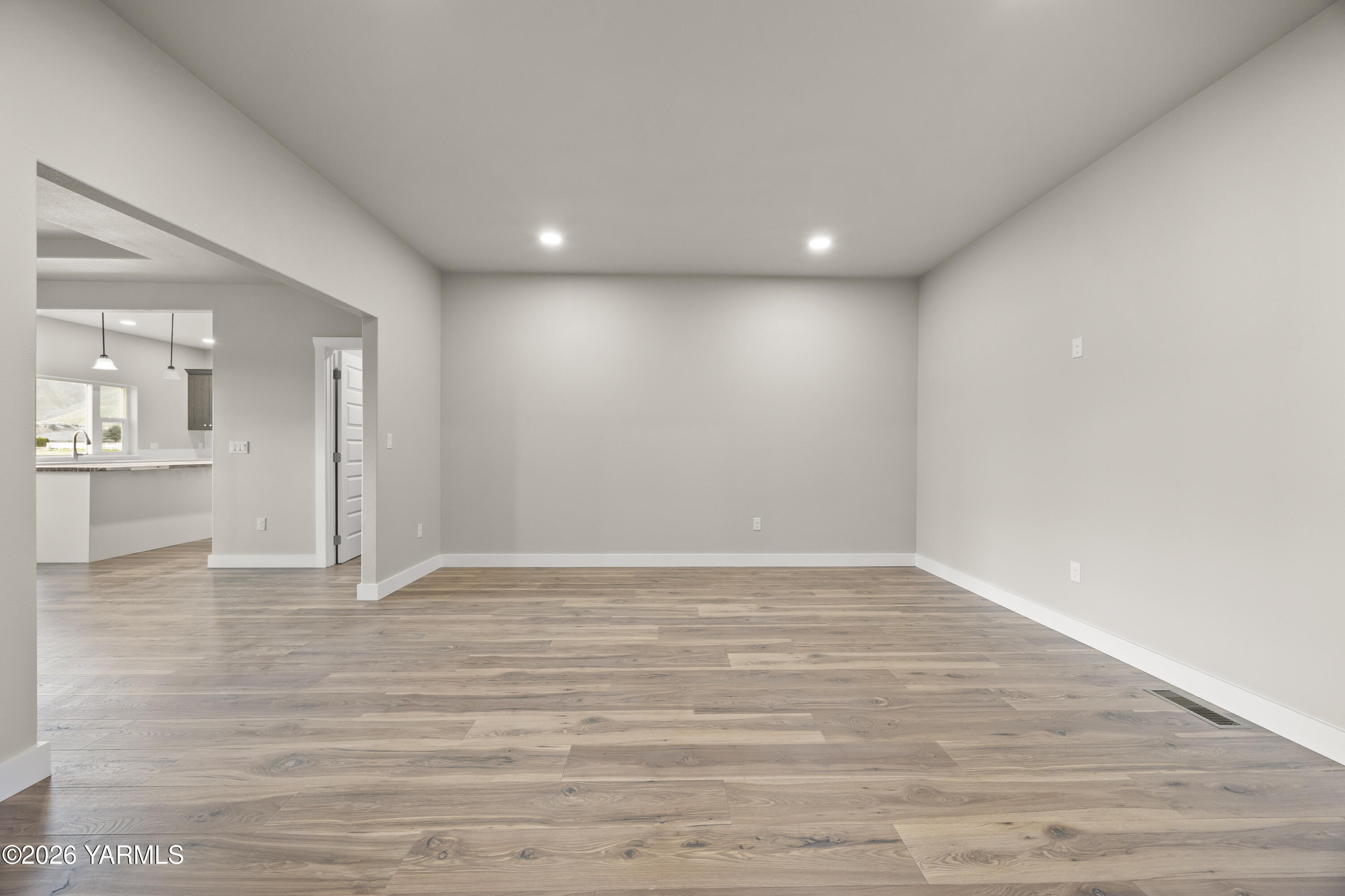 6133 South Moore Road Prosser, WA 99350 - Photo 9 of 54 a view of an empty room with wooden floor and a kitchen