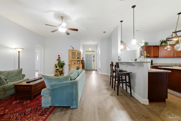a living room with furniture kitchen view and a wooden floor